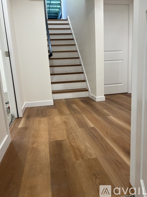 A hallway with wooden floors and a staircase.