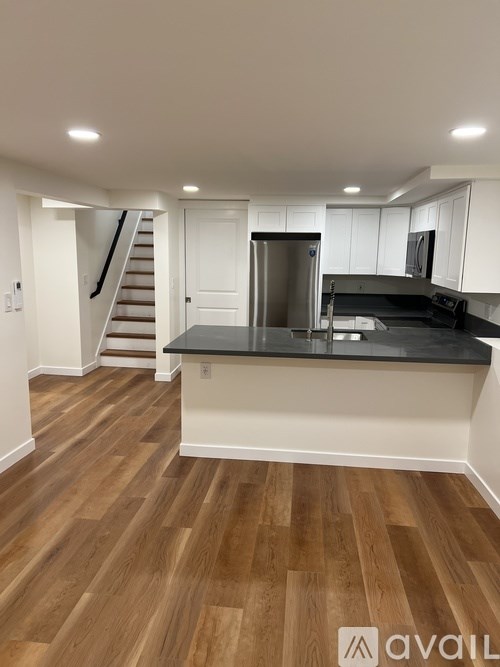 A kitchen with wooden floors and a black countertop.
