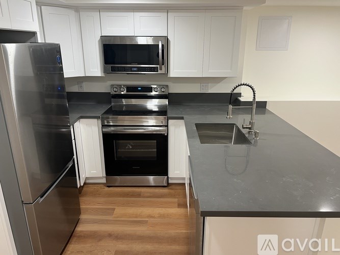 A kitchen with a stainless steel refrigerator and a black countertop.