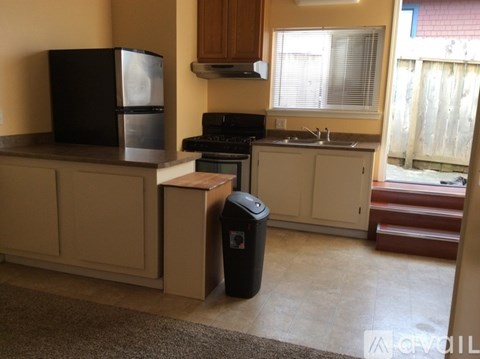 A kitchen with a black fridge, black stove, and black trash can.