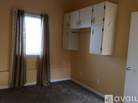 A room with a window, curtains, and a wall-mounted cabinet.