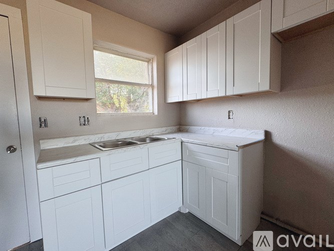 A kitchen with white cabinets and a window.