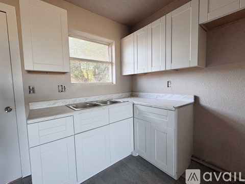A kitchen with white cabinets and a window.