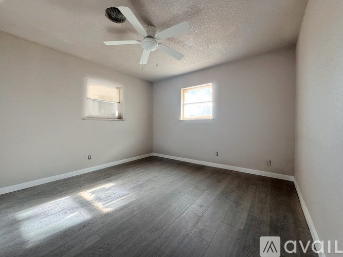 A room with a ceiling fan and two windows.