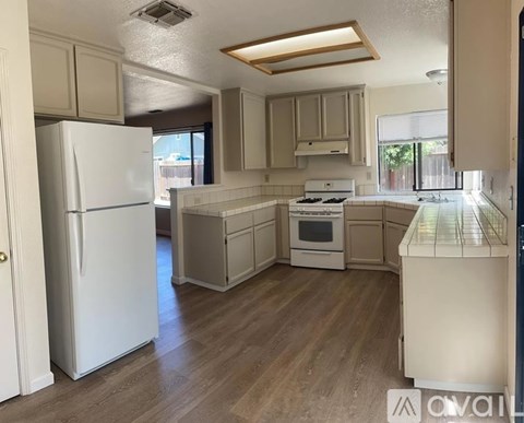 A kitchen with white appliances and wooden floors.