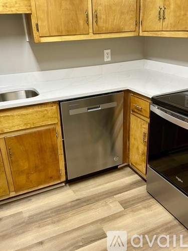A kitchen with wooden cabinets and a stainless steel dishwasher.