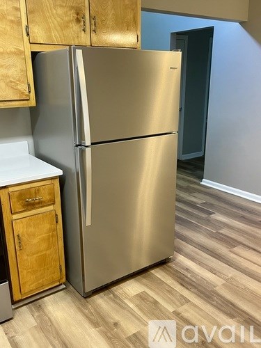 A stainless steel refrigerator in a kitchen with wooden cabinets.