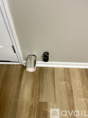A black and silver object is on a wooden floor next to a white door.