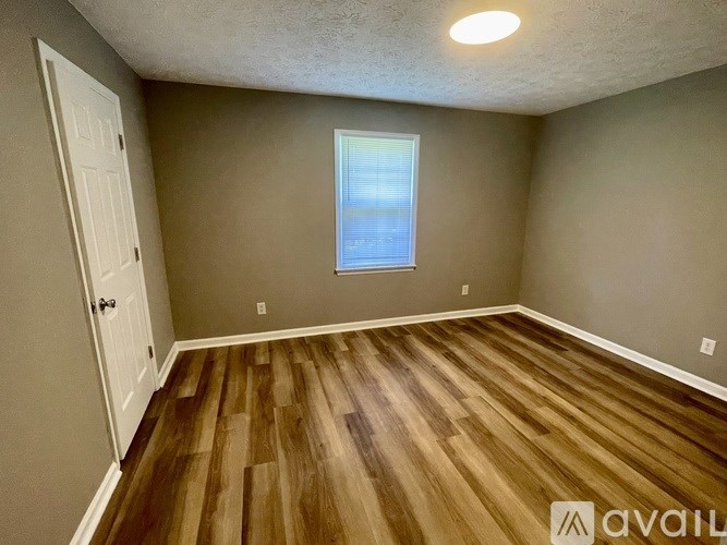 A room with wooden flooring and a window with blinds.