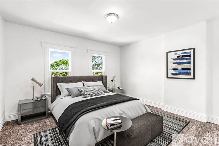 A bedroom with a large bed and a window showing greenery outside.