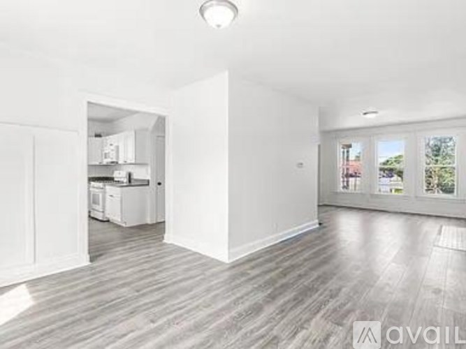 A spacious room with a kitchen in the background and a window overlooking a balcony.