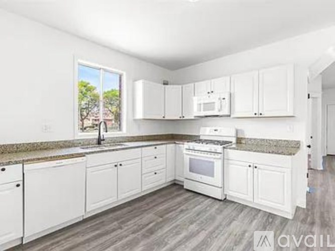 A kitchen with white cabinets and a granite countertop.