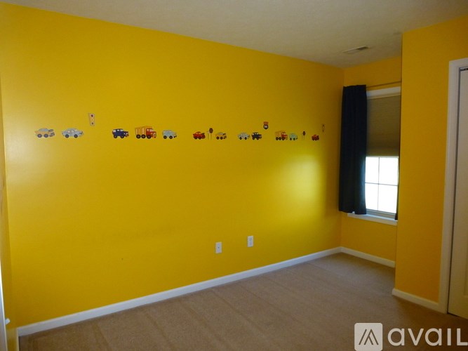 A room with yellow walls and toy cars on the wall.