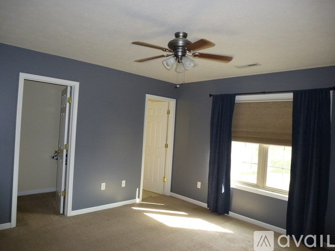 A room with a ceiling fan and a window with curtains.