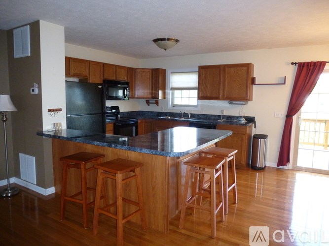 A kitchen with wooden cabinets and a black refrigerator.