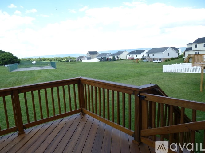 A wooden deck overlooks a grassy field with houses in the distance.