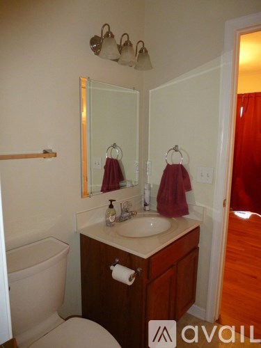 A bathroom with a toilet, sink, mirror and towel rack.