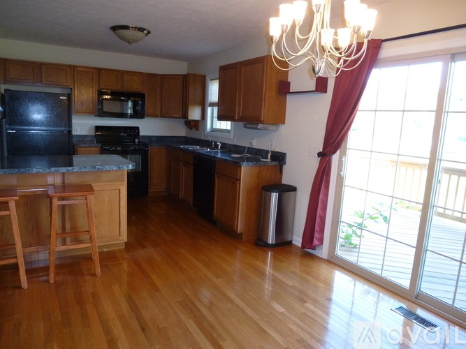 A kitchen with wooden floors and black appliances.