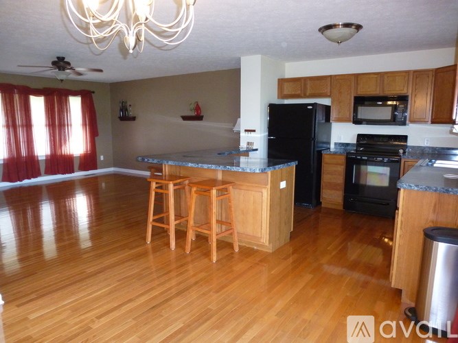 A kitchen with wooden floors and a black refrigerator.