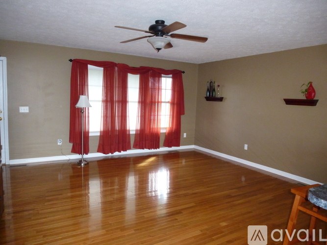 A room with a ceiling fan and red curtains.