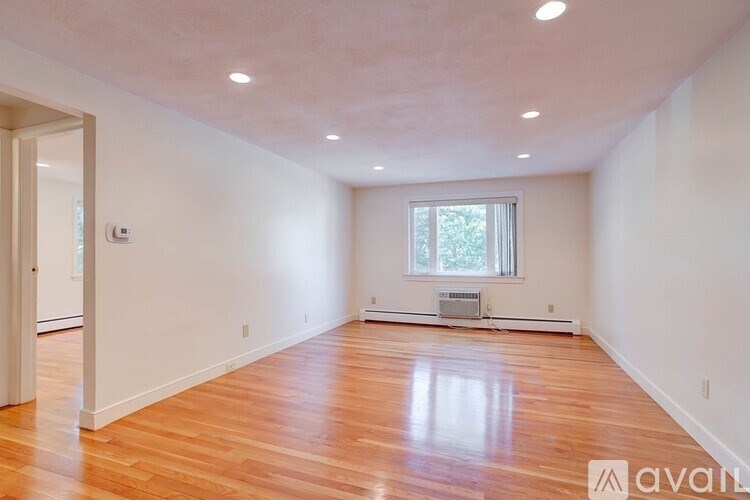 A room with wooden floors and a window with a view of trees.