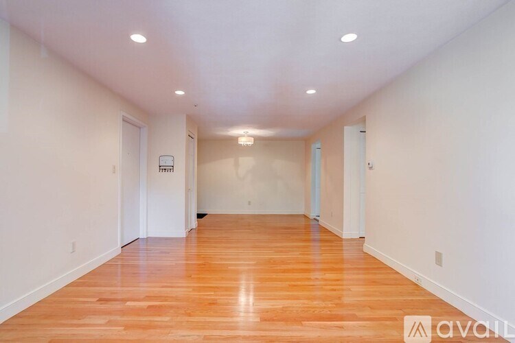 A long hallway with wood floors and white walls.