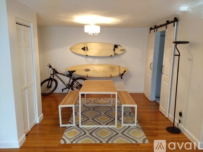 A room with a surfboard and a bicycle on the wall.