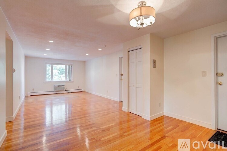 A room with wooden floors and white walls, with a chandelier hanging from the ceiling.