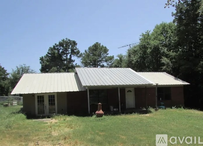A house with a metal roof is surrounded by greenery.