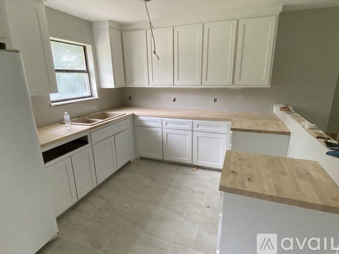 A kitchen with white cabinets and a wooden countertop.