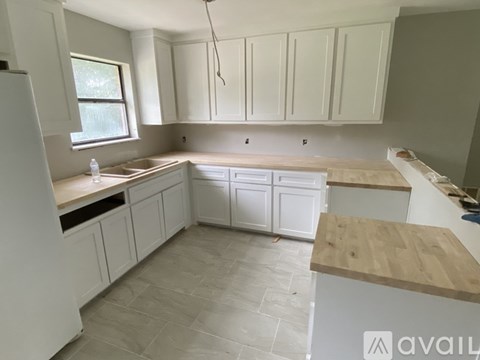 A kitchen with white cabinets and a wooden countertop.