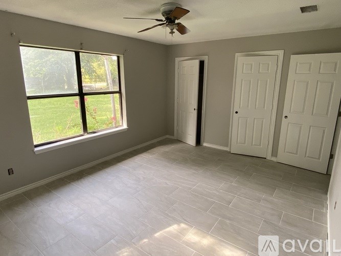 A room with a ceiling fan and a large window.