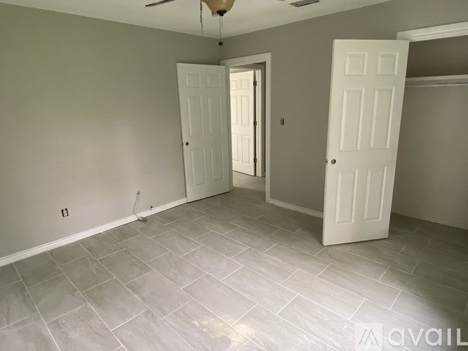 A room with tile flooring and two white doors.