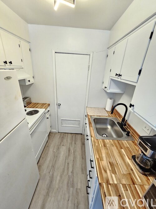A kitchen with white cabinets and a wooden counter top.