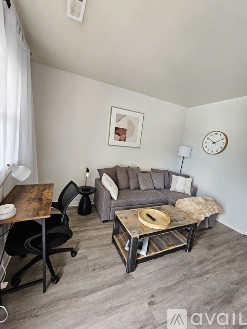 A living room with a grey couch, a wooden coffee table, and a black chair.