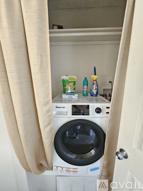 A washing machine with a bottle of detergent and a spray bottle on top of it.