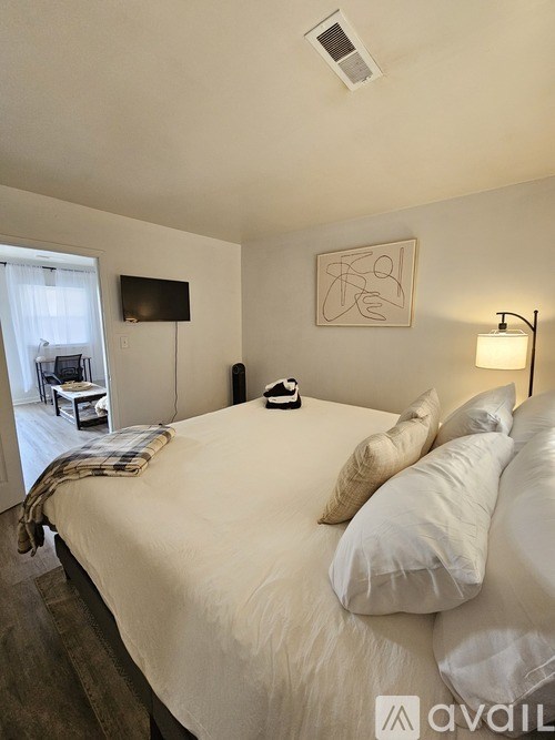 A bedroom with a large bed and a flat screen TV mounted on the wall.