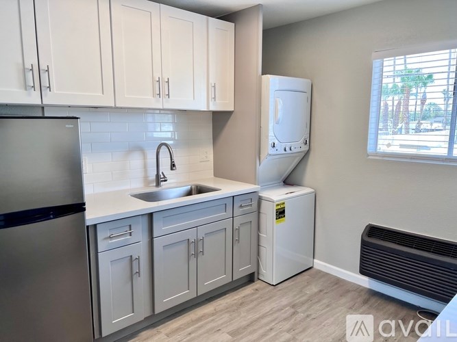 A kitchen with white cabinets and a black refrigerator.