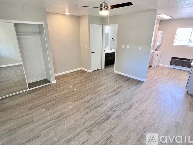 A room with a ceiling fan and light, and a wall with a window.