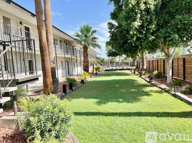 A sunny day at a well-kept apartment complex with a green lawn and palm trees.