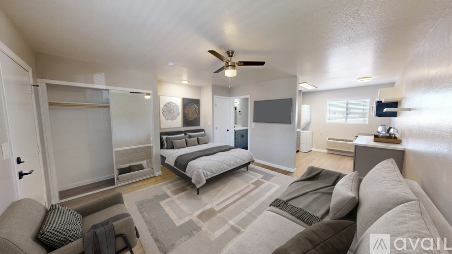 A modern living room with a grey sofa and a bed in the background.