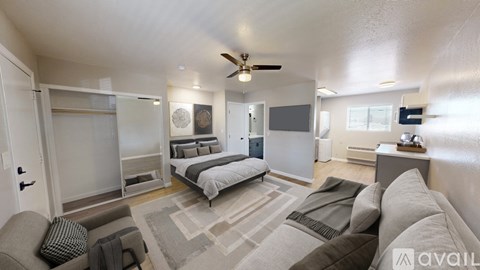 A modern living room with a grey sofa and a bed in the background.