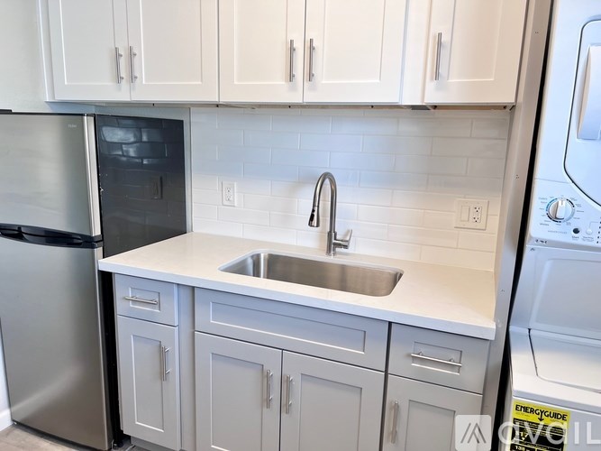 A kitchen with a stainless steel refrigerator and a white sink.