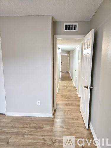 A hallway with white doors and a light brown floor.