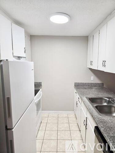 A kitchen with white cabinets and a white refrigerator.
