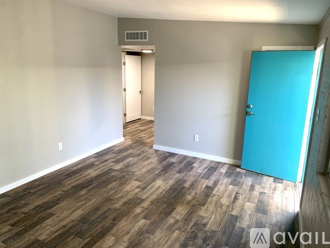 A room with a blue door and wood flooring.