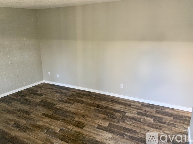 A room with wooden flooring and white walls is available for rent.
