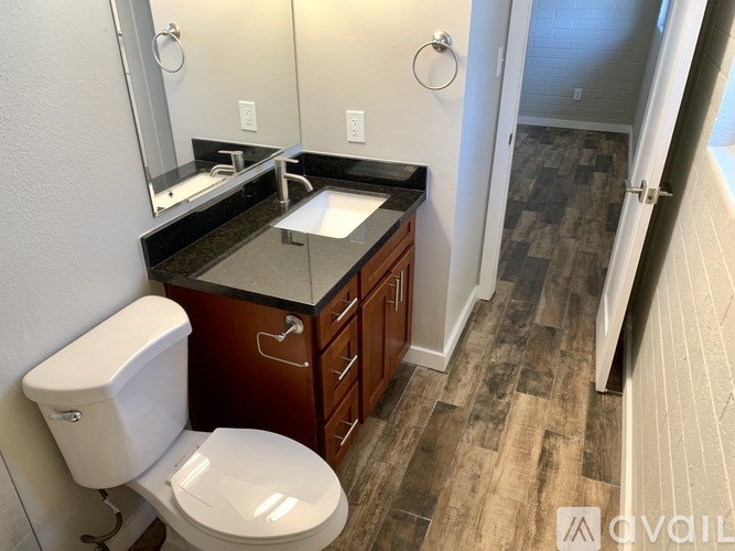 A bathroom with a toilet, sink, and mirror.
