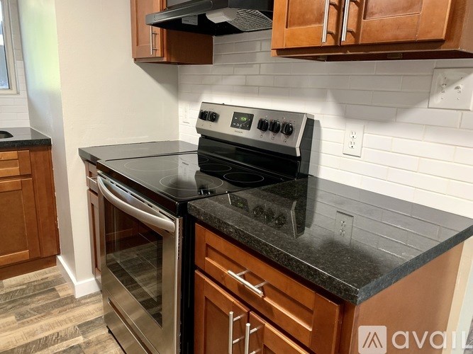 A kitchen with a black countertop and a stainless steel oven.