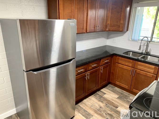 A stainless steel refrigerator stands in a kitchen with wooden cabinets.